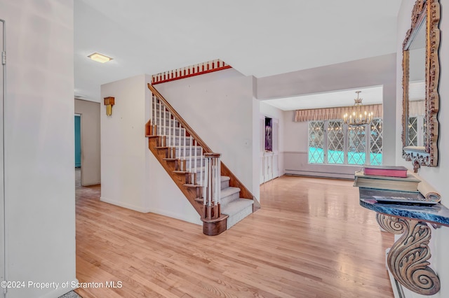 interior space with light wood-type flooring, a baseboard radiator, and a notable chandelier