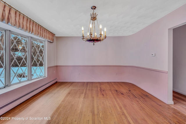 unfurnished room with a baseboard radiator, an inviting chandelier, and light hardwood / wood-style floors