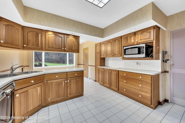 kitchen featuring backsplash, sink, light tile patterned floors, and stainless steel dishwasher