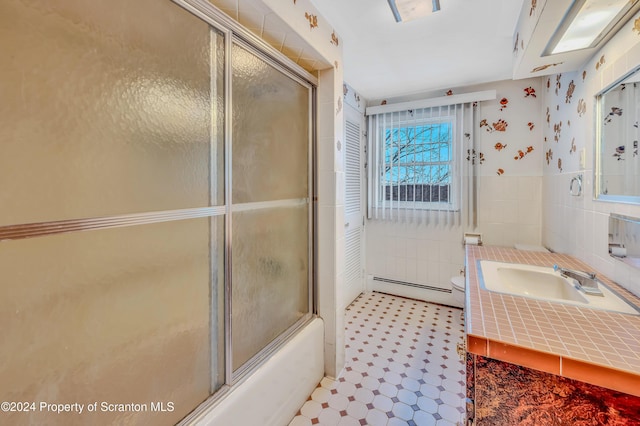 full bathroom featuring combined bath / shower with glass door, vanity, a baseboard radiator, tile walls, and toilet