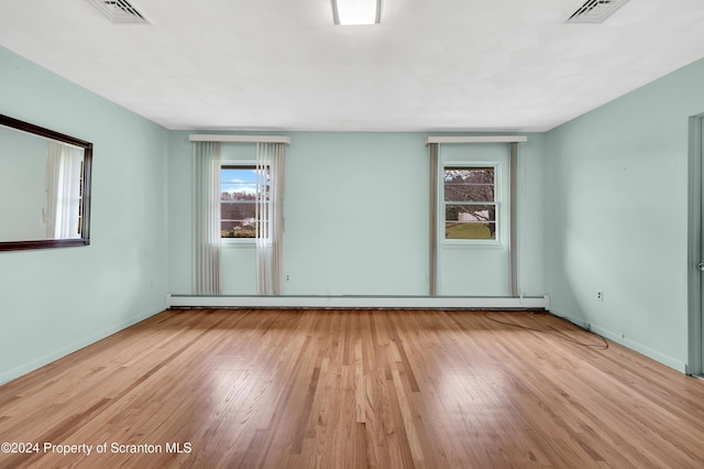 empty room with light hardwood / wood-style floors and a baseboard heating unit