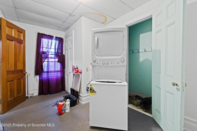 washroom with stacked washer and clothes dryer, wood finished floors, and laundry area