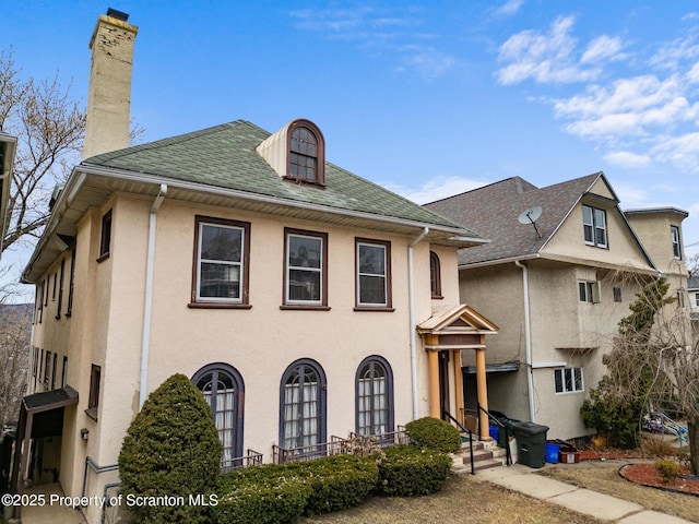 view of front of home with stucco siding and a chimney