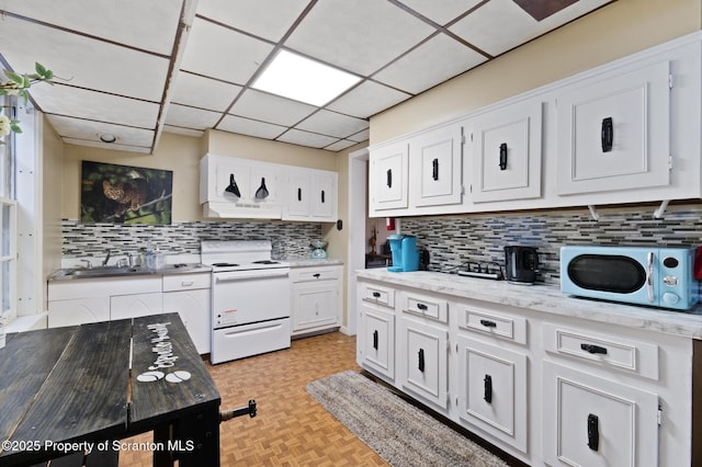 kitchen with tasteful backsplash, electric range, white cabinetry, a paneled ceiling, and a sink