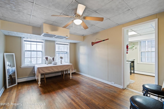 dining area featuring baseboard heating, a paneled ceiling, and hardwood / wood-style flooring