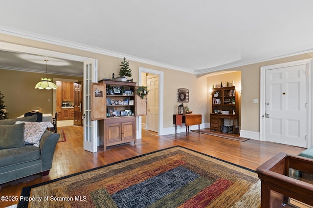 living room featuring wood finished floors, baseboards, french doors, and ornamental molding