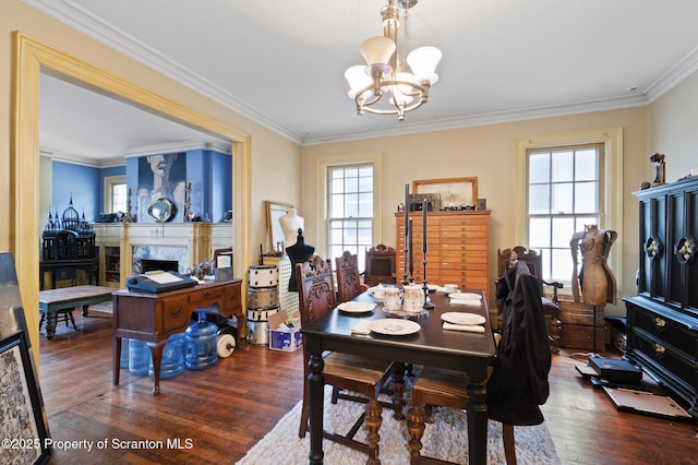 dining area with a premium fireplace, a notable chandelier, wood finished floors, and crown molding