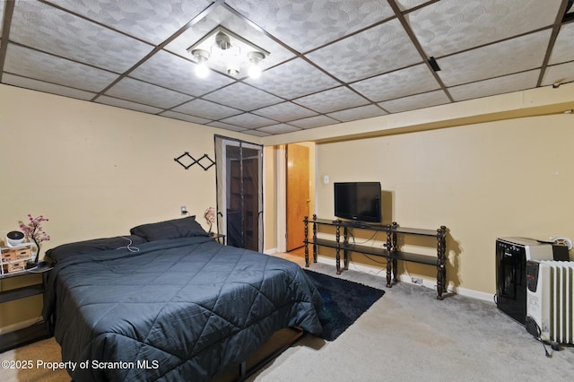 carpeted bedroom featuring a drop ceiling and baseboards