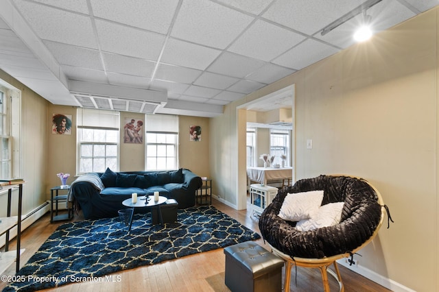 living area with wood finished floors, baseboards, and a drop ceiling