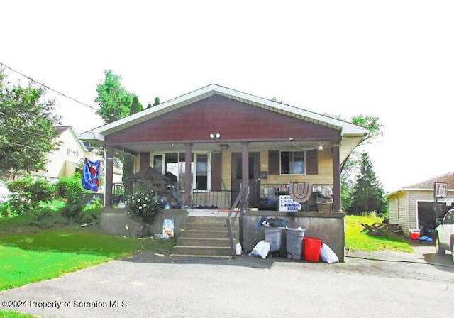 bungalow featuring covered porch and a front yard