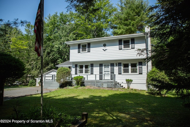 colonial house featuring an outbuilding and a front lawn