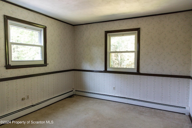 carpeted spare room featuring a baseboard heating unit, a wealth of natural light, and crown molding