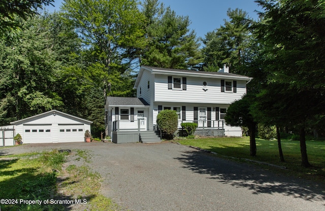 colonial inspired home featuring a front yard, a porch, a garage, and an outdoor structure