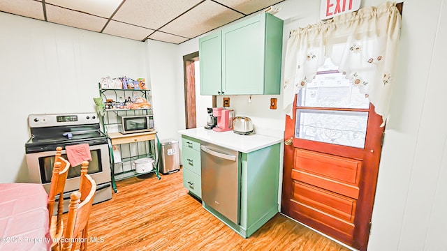 kitchen featuring green cabinets, a drop ceiling, light hardwood / wood-style floors, and appliances with stainless steel finishes