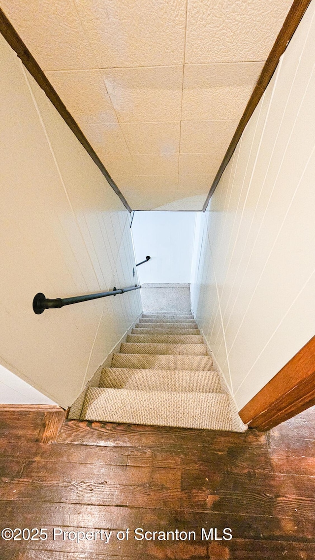 staircase featuring hardwood / wood-style flooring and wood walls