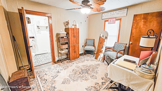 office featuring baseboard heating, wooden walls, and ceiling fan