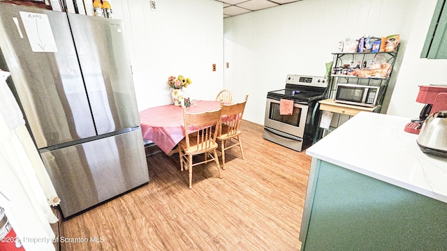 kitchen with appliances with stainless steel finishes, light wood-type flooring, a drop ceiling, and green cabinetry