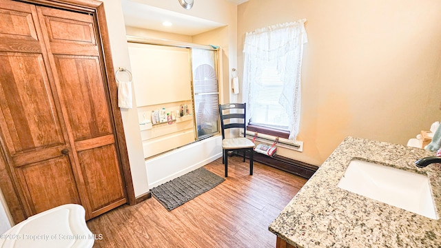 bathroom with hardwood / wood-style floors, vanity, and combined bath / shower with glass door