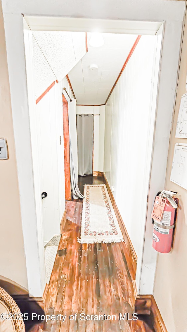 hallway featuring hardwood / wood-style flooring and wooden walls