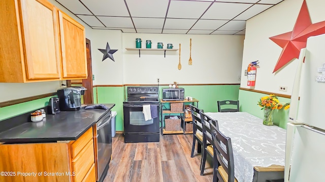 kitchen with black appliances, a paneled ceiling, and light wood-type flooring