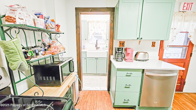 kitchen featuring range, green cabinets, sink, and light hardwood / wood-style flooring