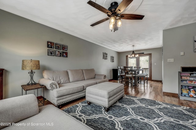 living room with hardwood / wood-style floors and ceiling fan with notable chandelier