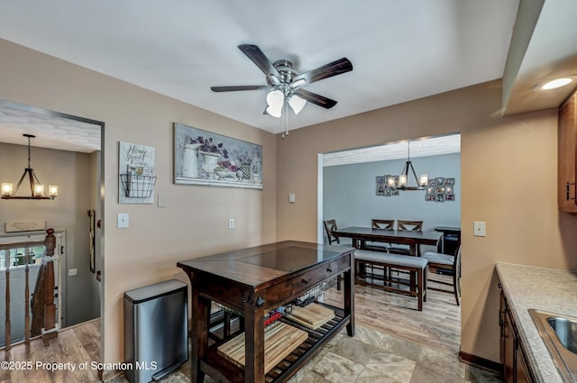 dining area featuring sink and ceiling fan with notable chandelier