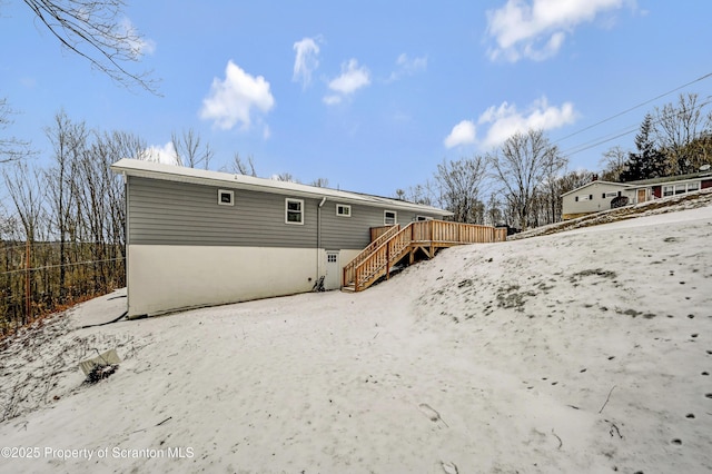 snow covered back of property featuring a wooden deck