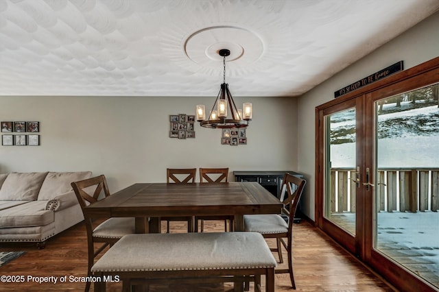 dining space featuring hardwood / wood-style floors, a notable chandelier, and french doors