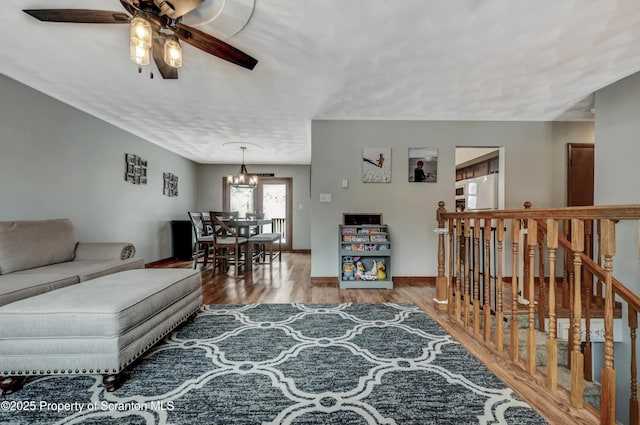 living room with ceiling fan with notable chandelier and hardwood / wood-style floors