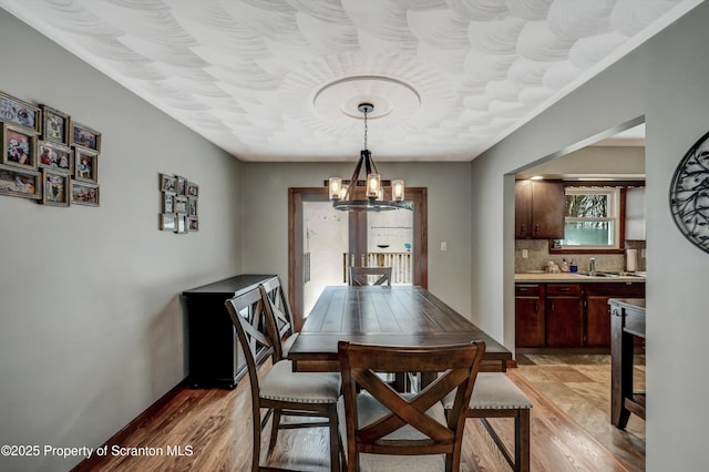 dining area with sink, light hardwood / wood-style floors, and a chandelier