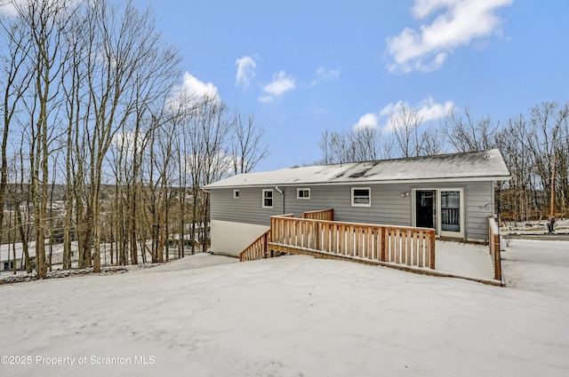 snow covered rear of property with a deck