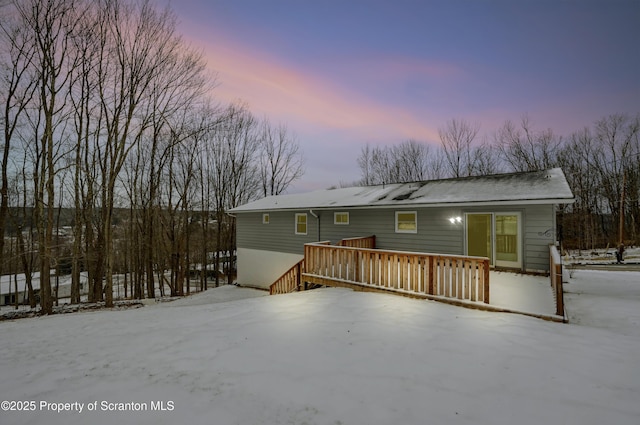 snow covered rear of property featuring a wooden deck