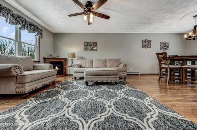 living room with hardwood / wood-style flooring, a baseboard radiator, and ceiling fan with notable chandelier