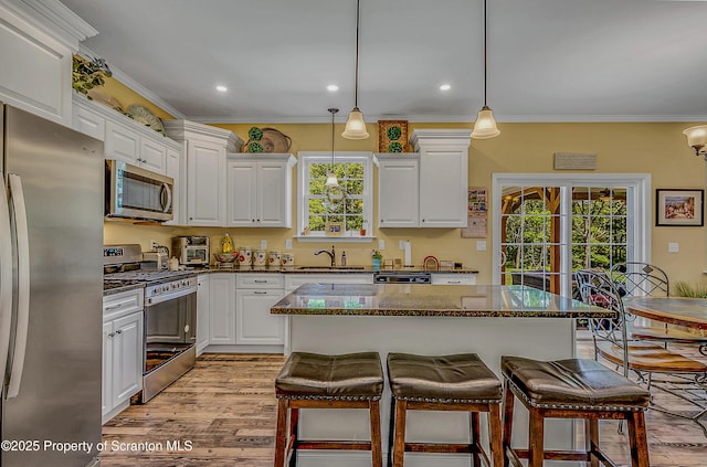 1612 Whitetail Run, Moscow, PA 18444 - kitchen featuring appliances with stainless steel finishes, white cabinetry, ornamental molding, a kitchen bar, and light wood-style floors