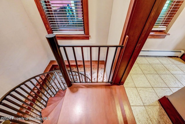 staircase featuring hardwood / wood-style flooring and baseboard heating