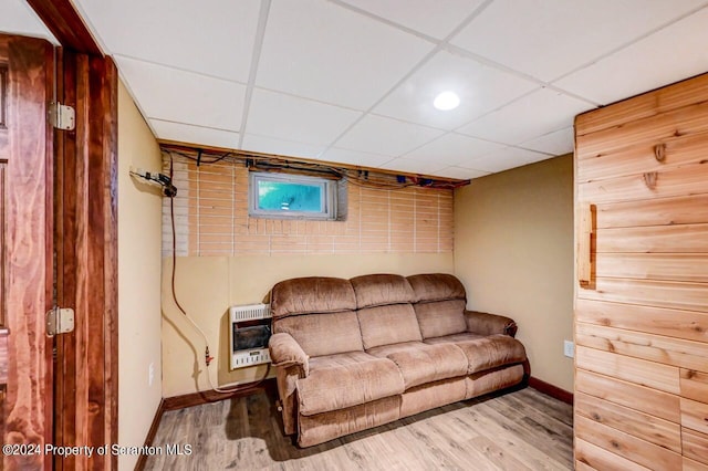 living room featuring hardwood / wood-style floors, heating unit, and a drop ceiling