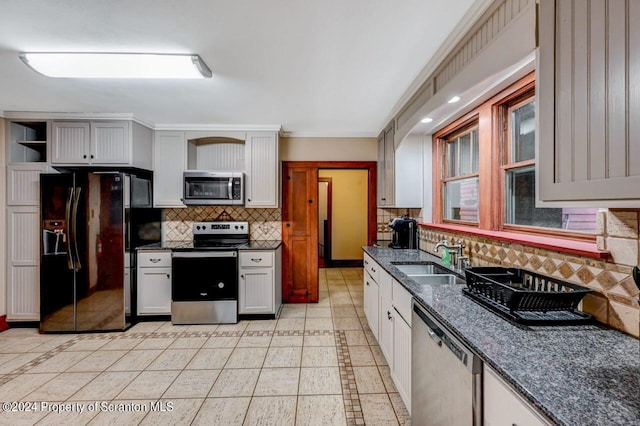 kitchen featuring sink, decorative backsplash, light tile patterned floors, appliances with stainless steel finishes, and white cabinetry