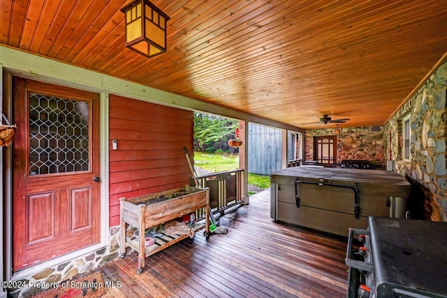 wooden deck with ceiling fan, a hot tub, and a storage unit