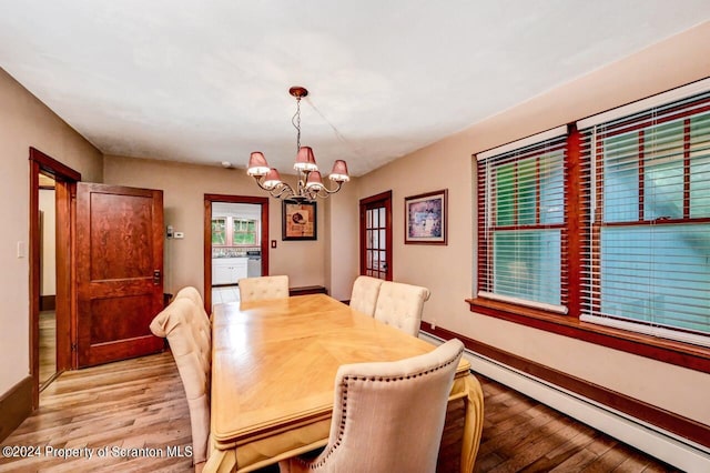 dining space with baseboard heating, light hardwood / wood-style floors, and a notable chandelier