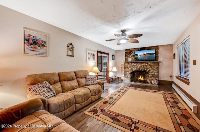 living room featuring a stone fireplace, ceiling fan, hardwood / wood-style floors, and a baseboard heating unit