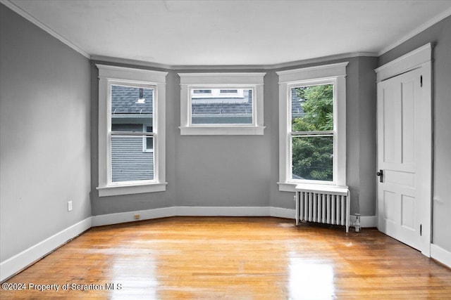 spare room featuring radiator heating unit, crown molding, and light hardwood / wood-style flooring