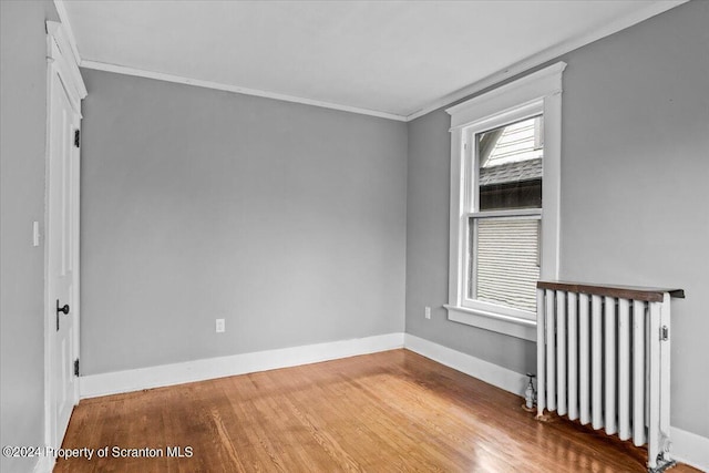 spare room featuring radiator heating unit, crown molding, and wood-type flooring