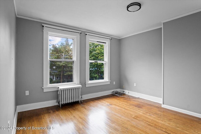 spare room with crown molding, radiator, and light hardwood / wood-style flooring