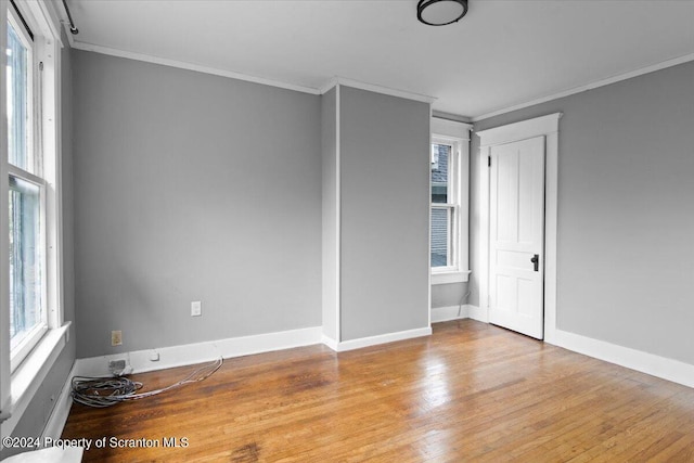 spare room with plenty of natural light, light wood-type flooring, and crown molding