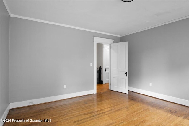 empty room with light hardwood / wood-style floors and crown molding