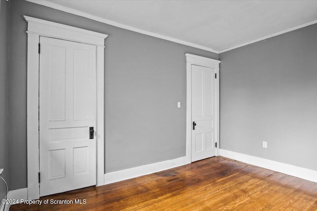 unfurnished bedroom with ornamental molding and dark wood-type flooring