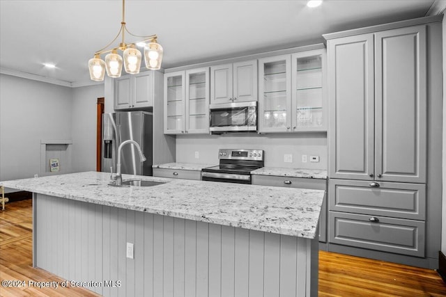 kitchen featuring sink, stainless steel appliances, gray cabinets, a kitchen island with sink, and light wood-type flooring