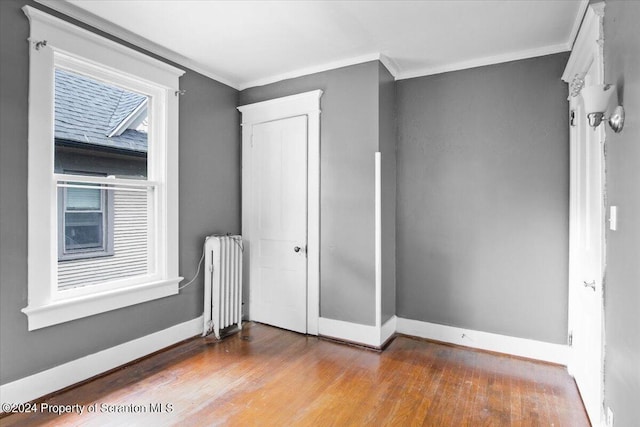 unfurnished bedroom featuring hardwood / wood-style flooring, radiator, and crown molding