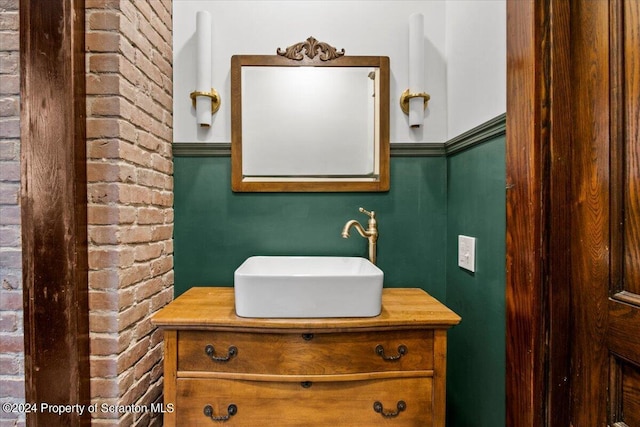 bathroom featuring vanity and brick wall